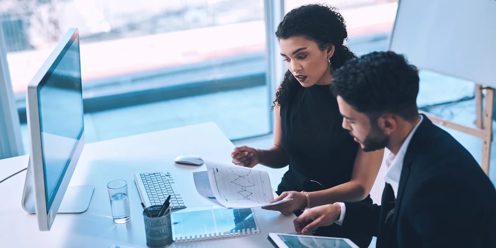Two colleagues working through the month's numbers together at a desk
