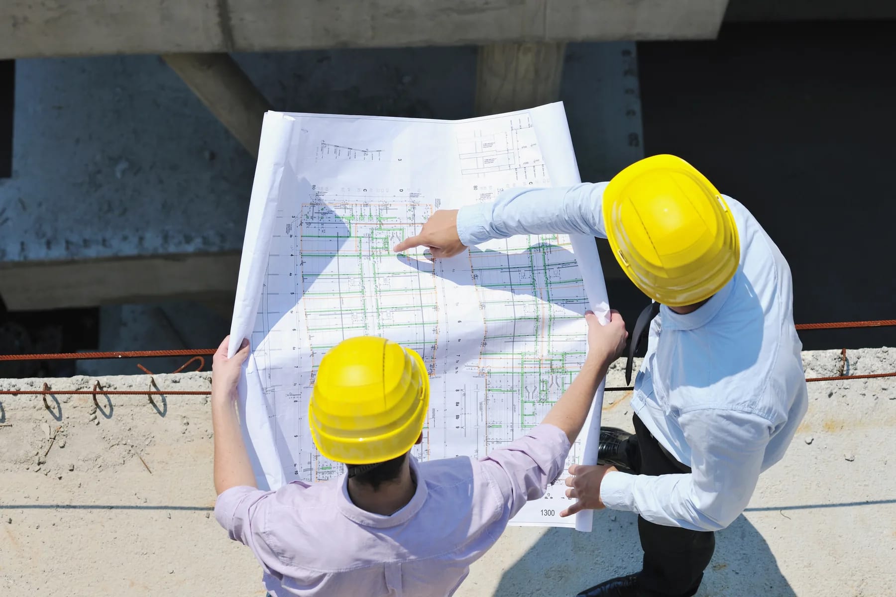 Two engineers measuring quantities off a drawing set on site