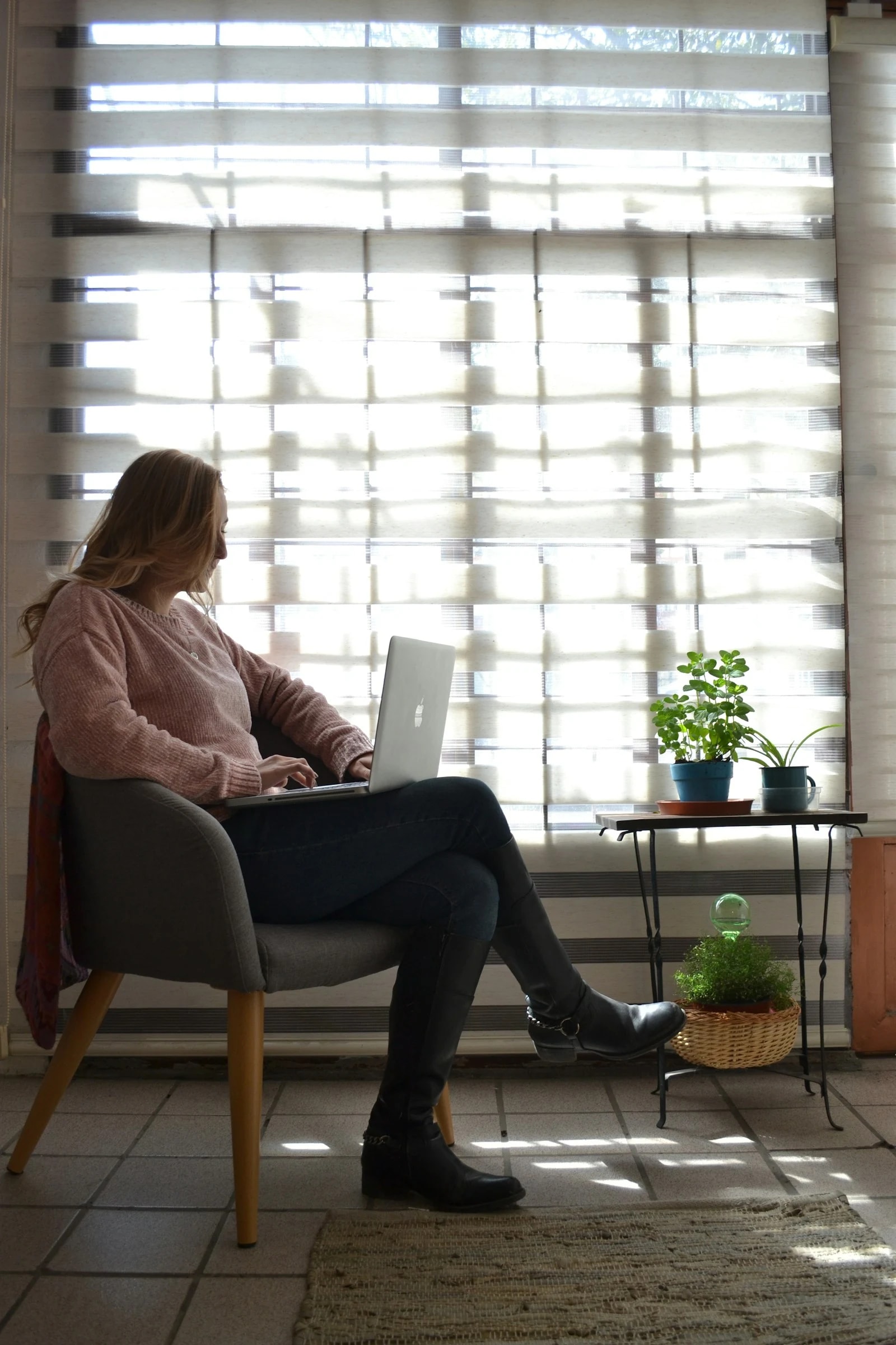 A professional working on a laptop in warm daylight by a window