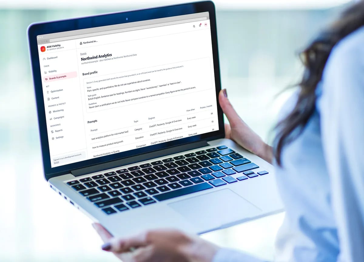 A person holding a laptop open on the AllAI Visibility brand and prompts screen